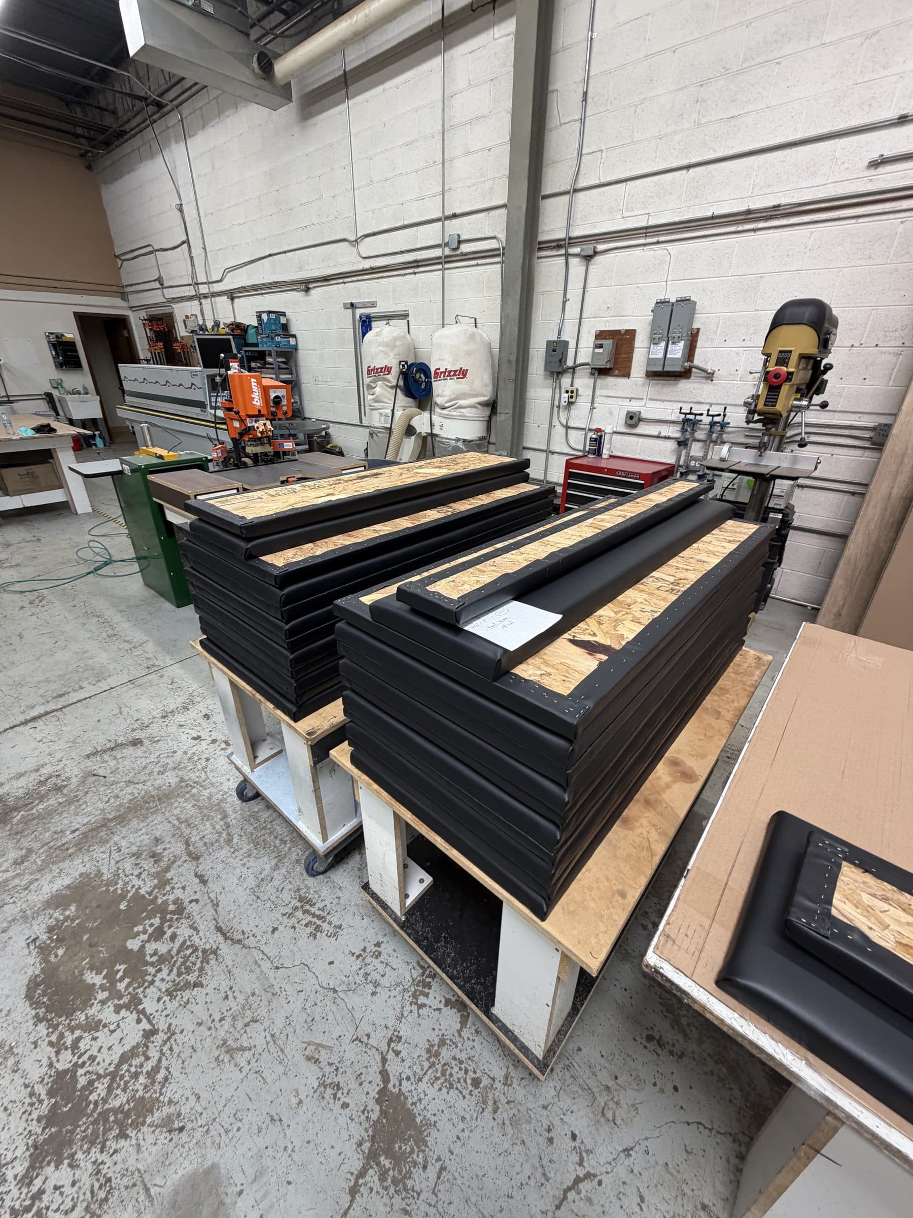 Stacks of completed custom vinyl golf simulator panels staged in the workshop before installation