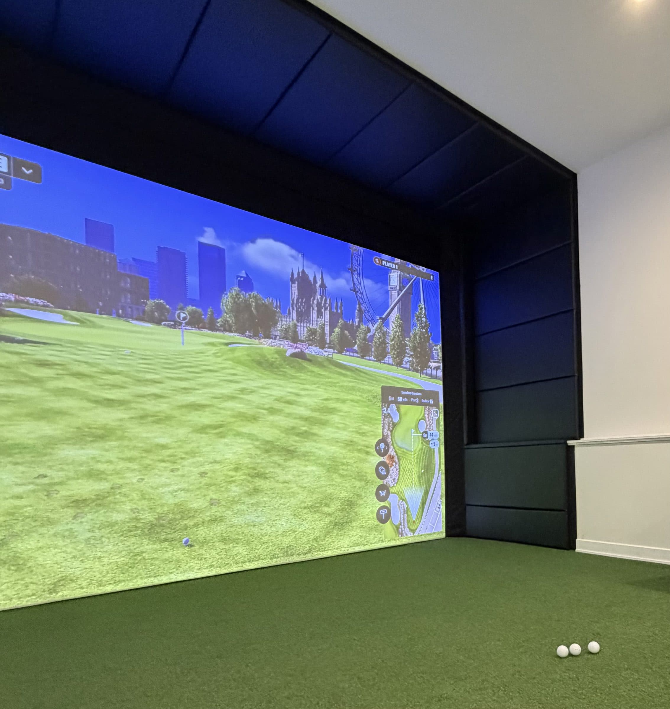 Golf simulator bay framed in matte black vinyl wall panels around the impact screen