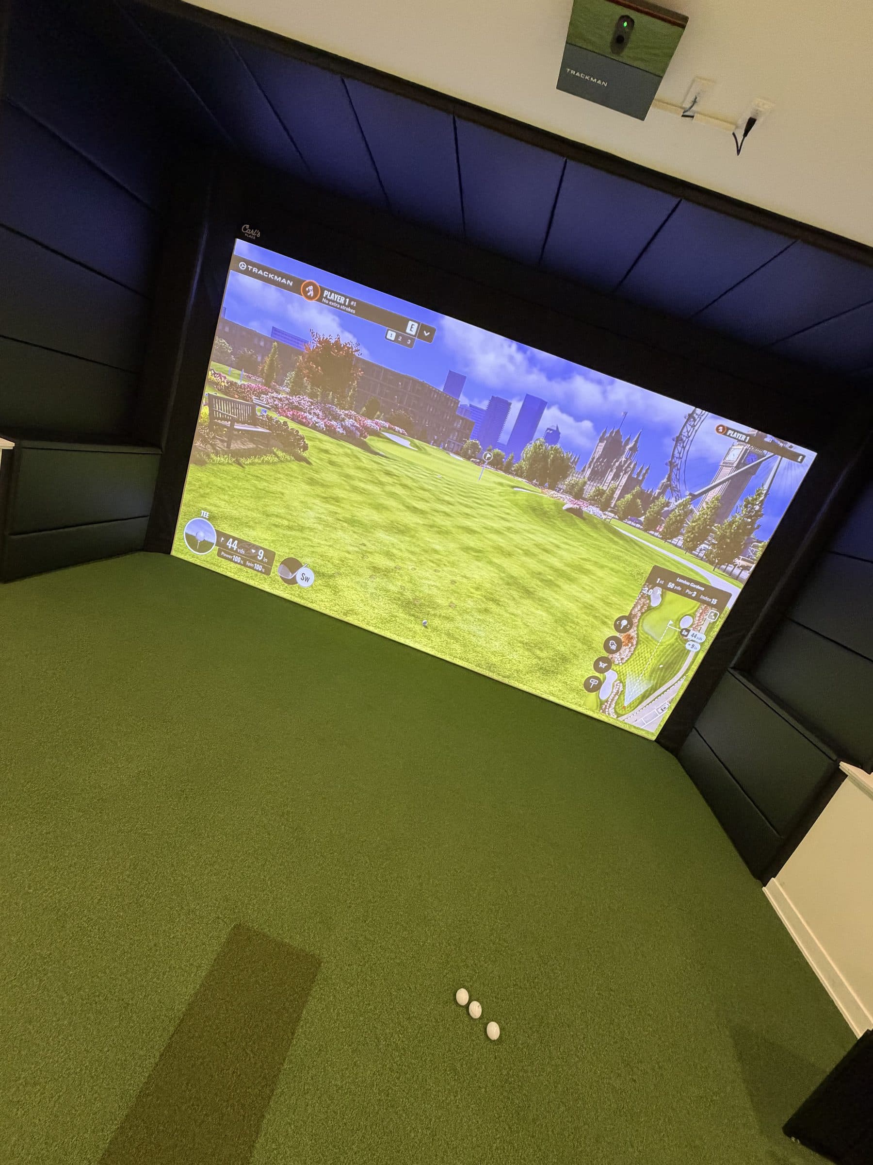 Angled view of a golf simulator room with panelled side walls and ceiling