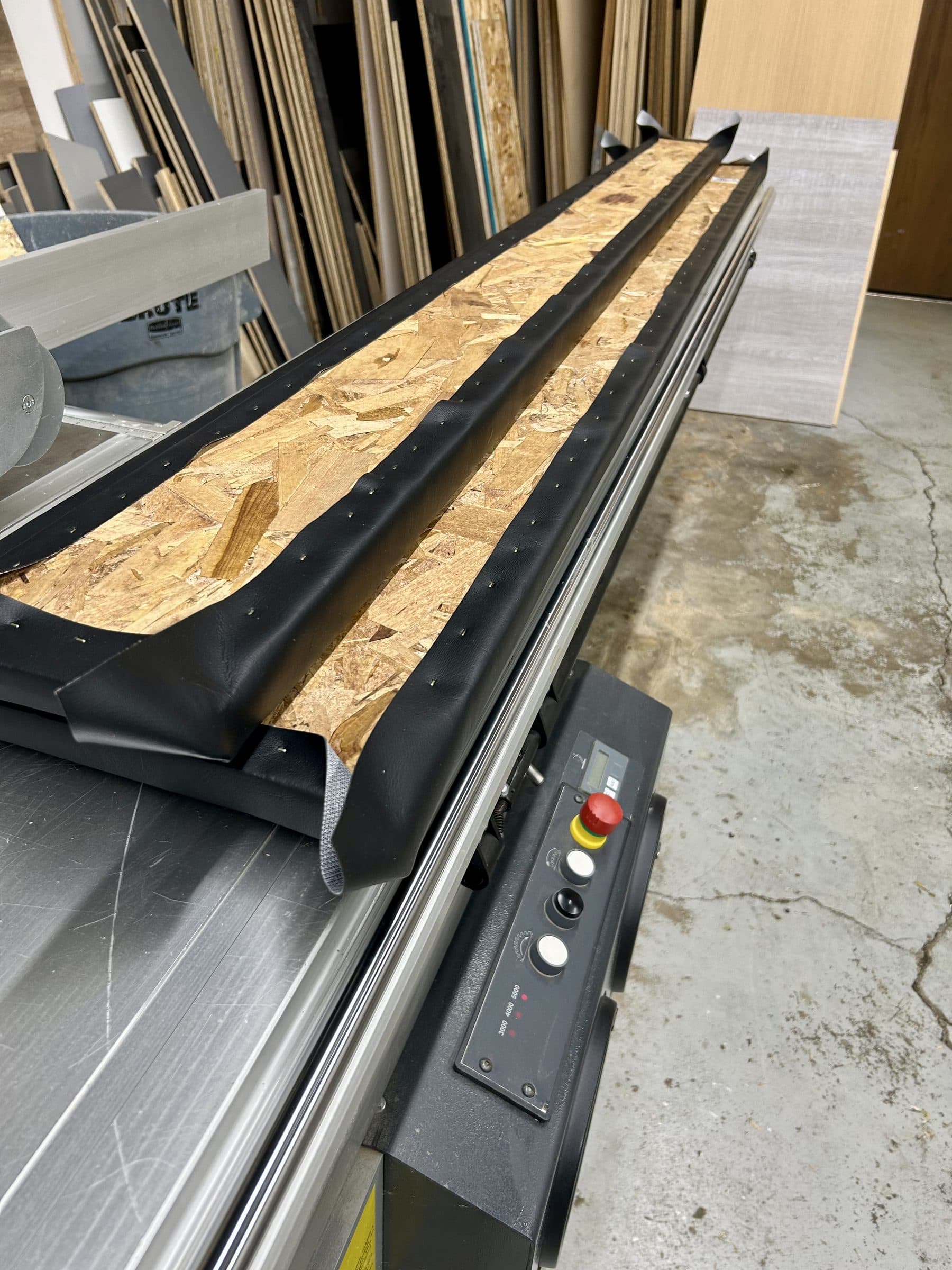 A long simulator wall panel being upholstered, with vinyl stapled along the OSB backing