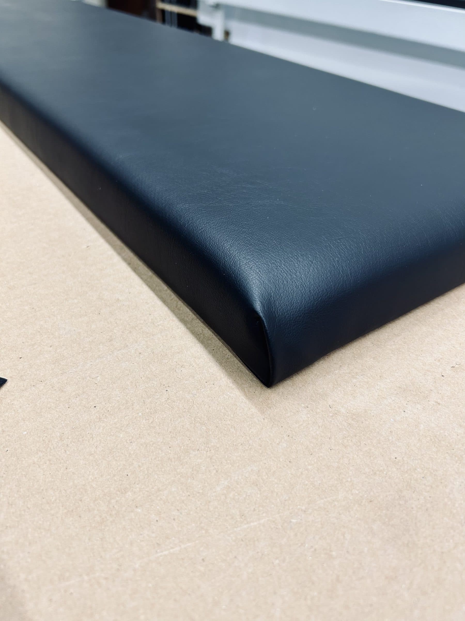 Close-up of a padded vinyl panel edge showing the high-density foam depth under the vinyl
