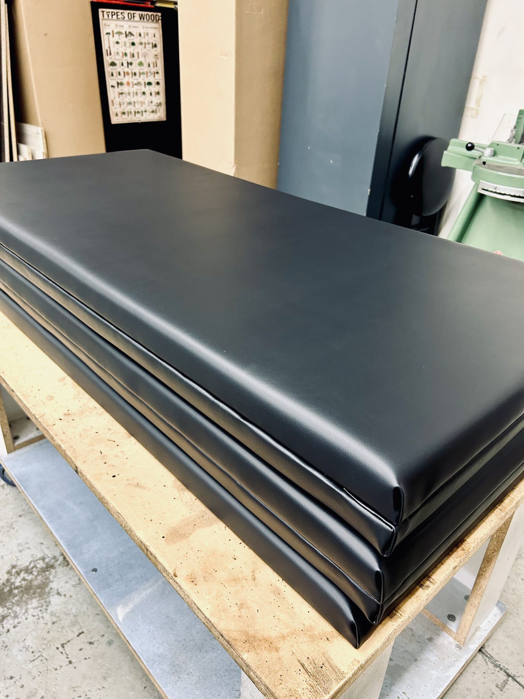 A stack of finished golf simulator wall panels upholstered in matte black vinyl
